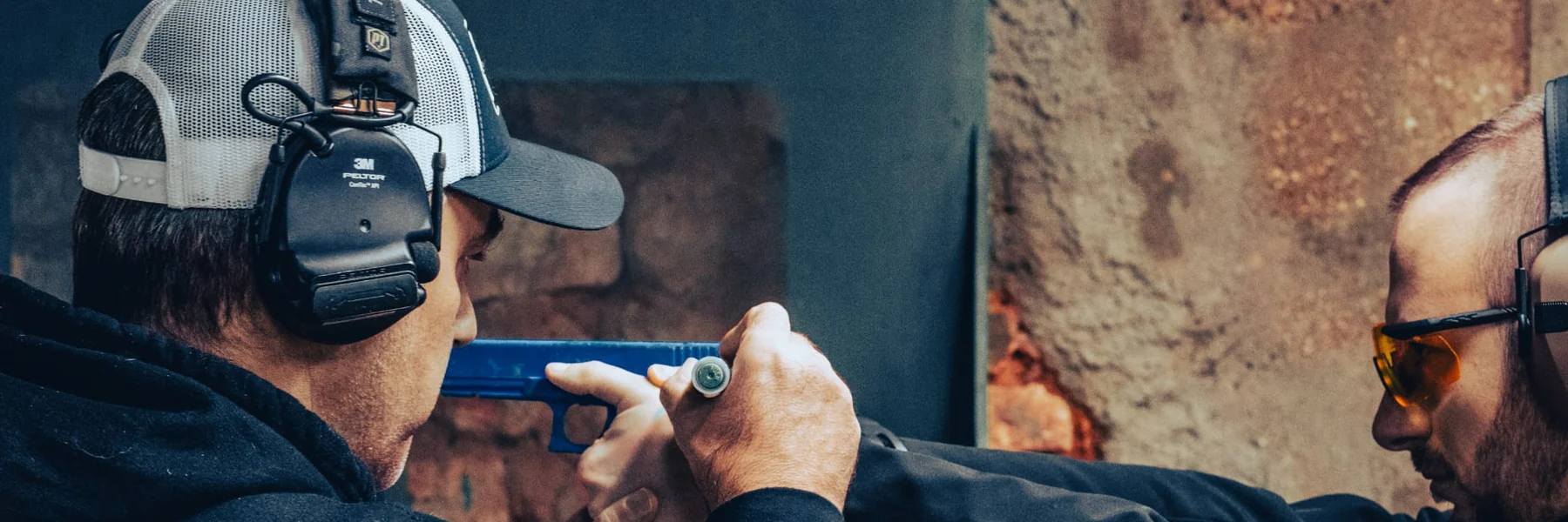 Le moniteur corrige la prise en main et l'alignement d'un tireur au pistolet, protections auditives portées