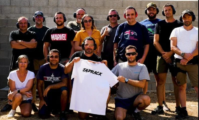 Groupe de stagiaires posant avec un t-shirt TAP RACK après une journée de tir